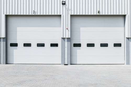 Garage Door Track closeup door off track while repairing Commercial garage door repair closeup while servicing door hardware