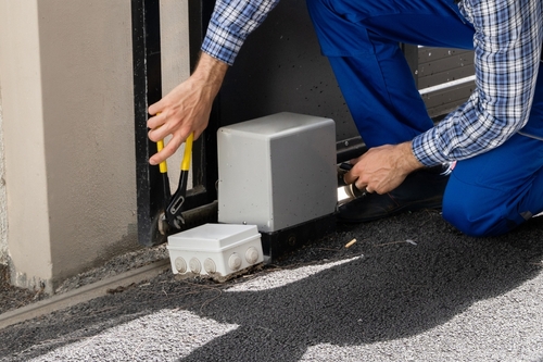 Professional garage door technician inspecting a heavy-duty torsion spring during a repair service in North Texas.